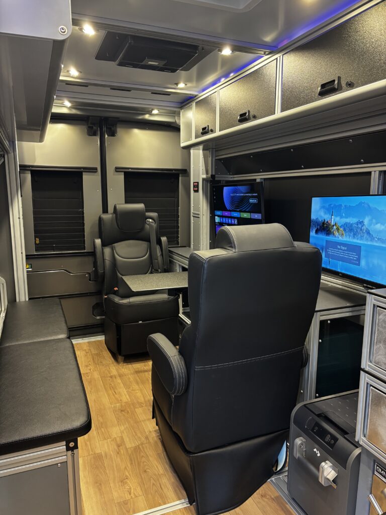 Vandoit unit interior with two facing swivel captain chairs and a wall-mounted client screen